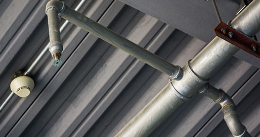 Fire sprinkler piping and detector on a commercial ceiling